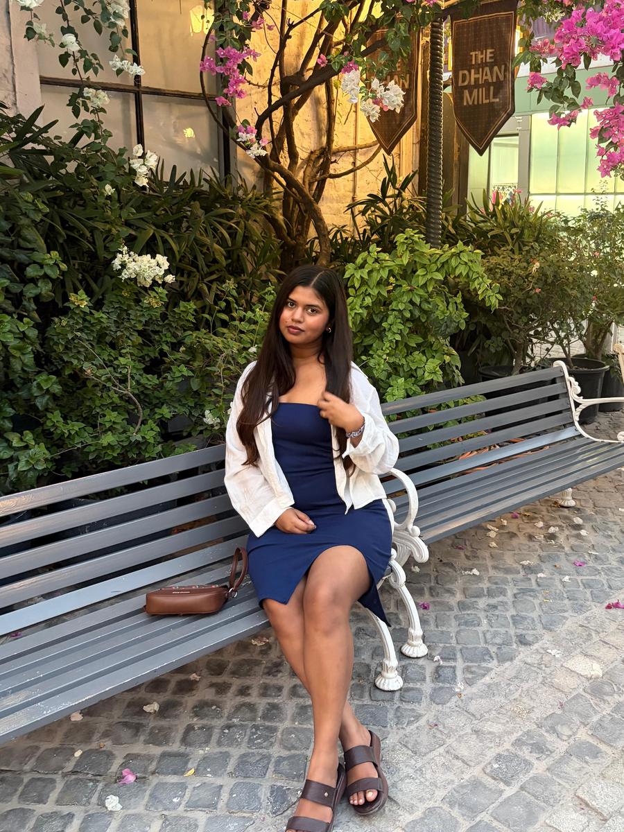 Khushi seated on a bench under bougainvillea at The Dhan Mill
